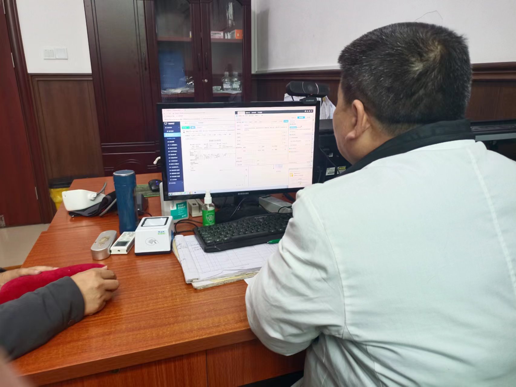 圖一 浮梁縣三龍衛生院中醫師吳志平在通過智能輔助診療系統為病人看病.jpg