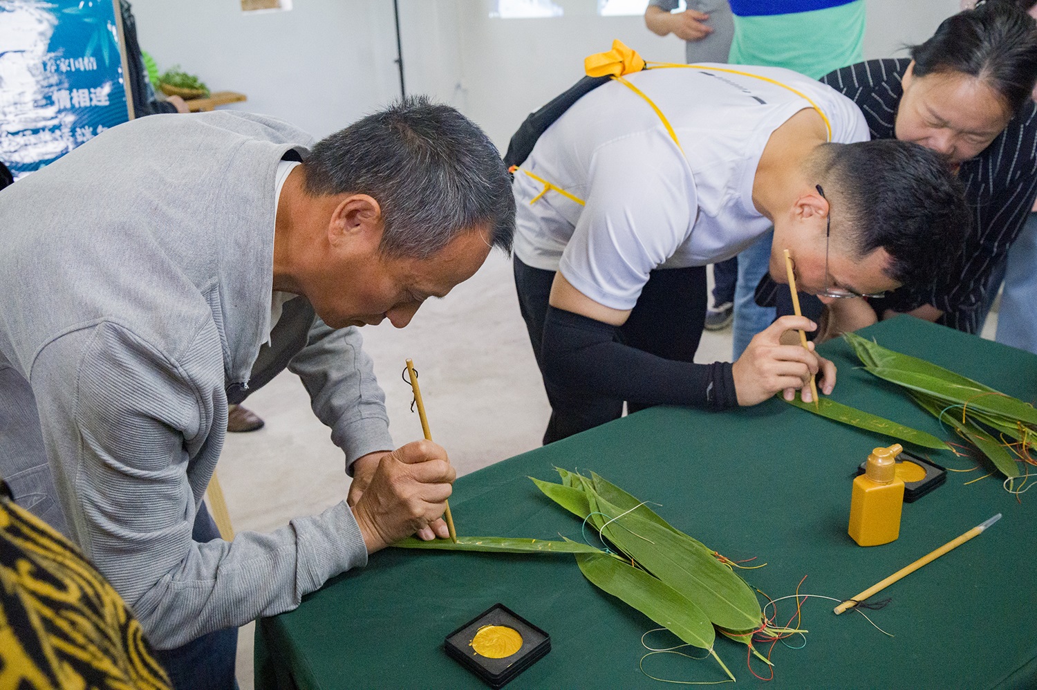 图一：金溪会场现场用毛笔在粽叶上签名（李山冕 摄）.jpg