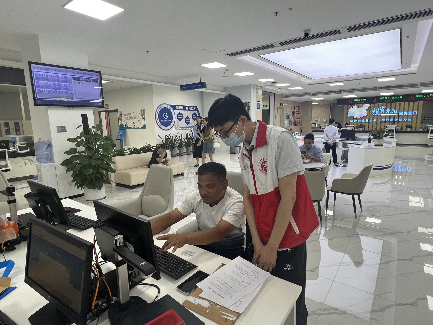 2、在惠陽區政務服務大廳，志願者為辦事人員解疑答惑。.jpg