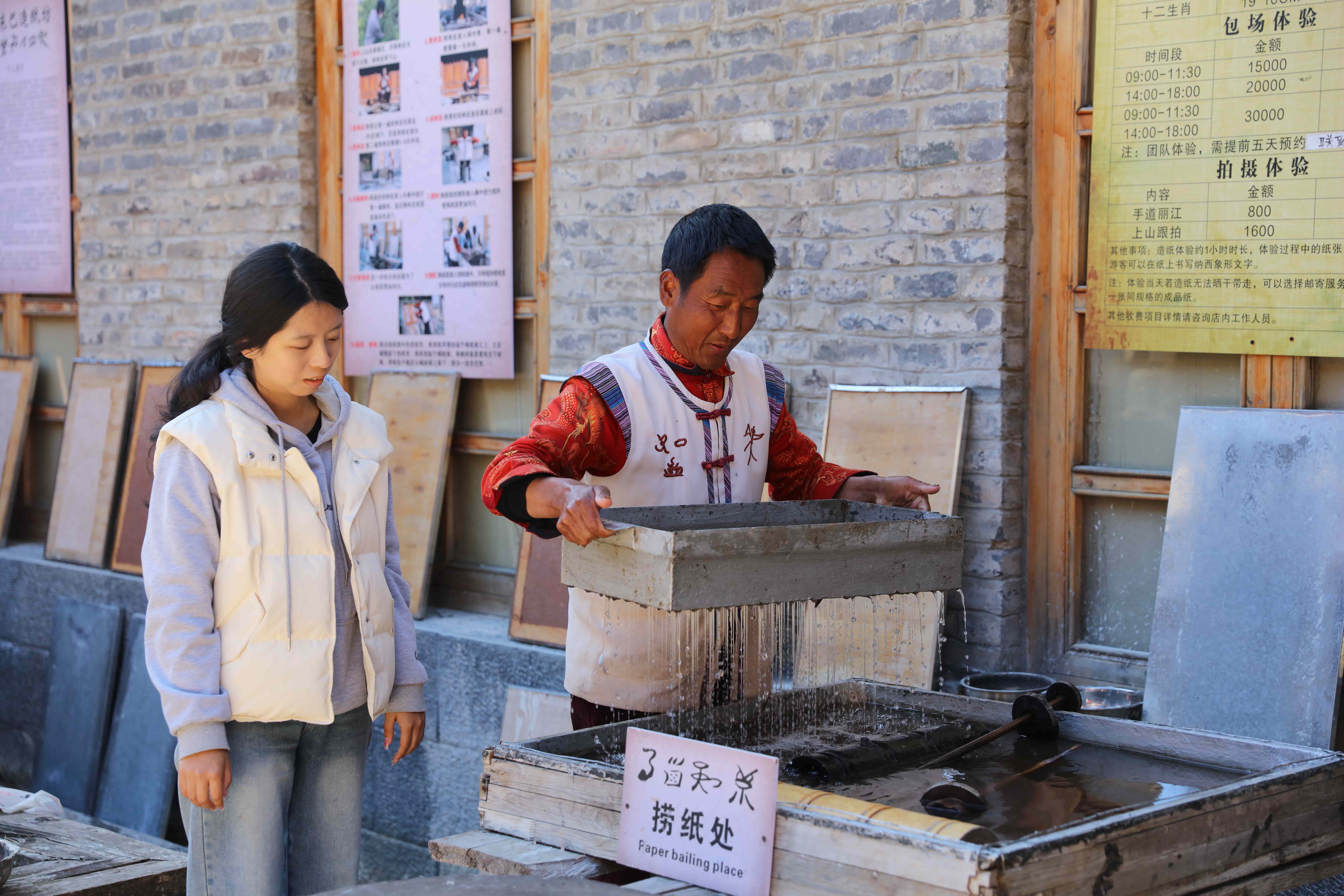 图4:东巴纸非遗传承人和秀昌向游客展示造纸技艺 王冰 摄.JPG