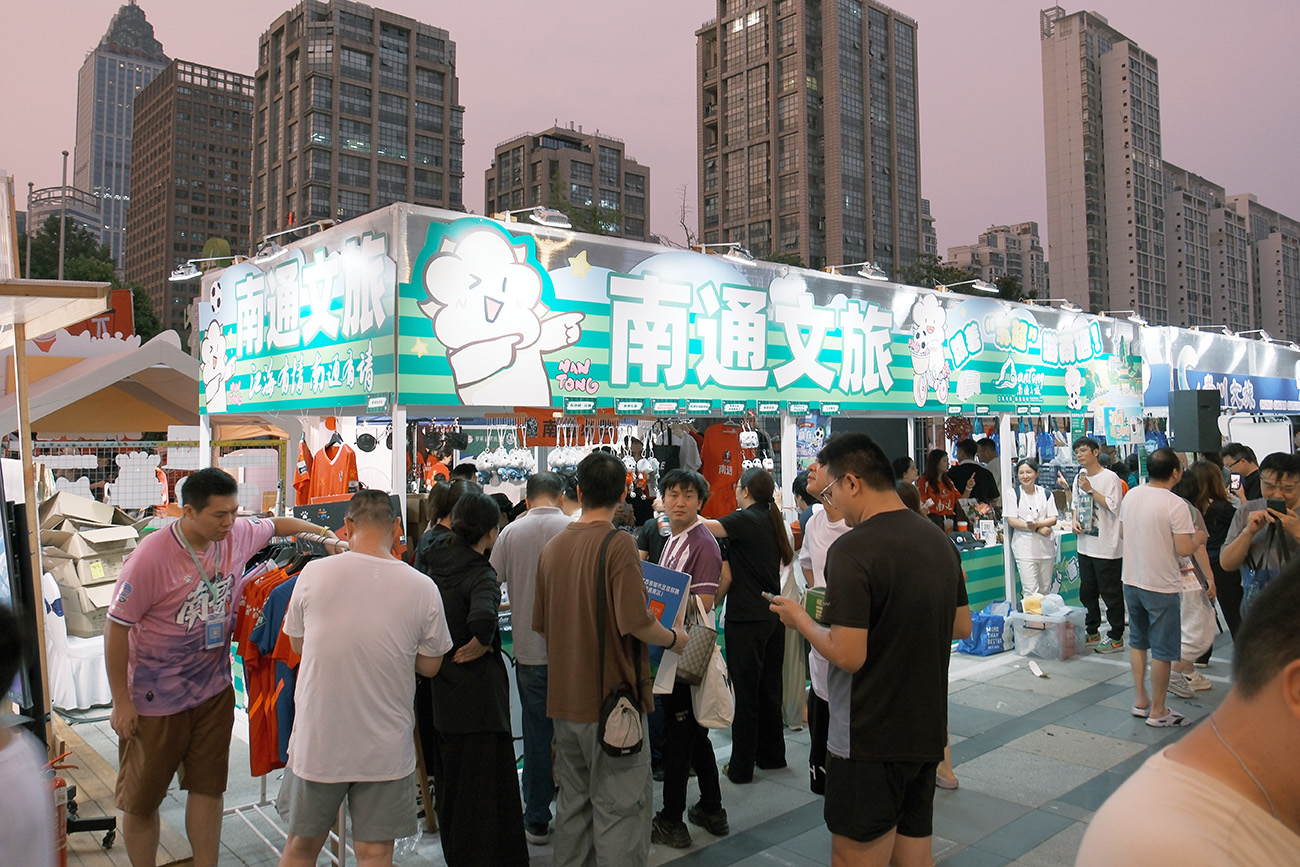 圖2:南通文旅攤位,「通通」蘇超玩偶、狼狼玩偶,藍印花布蘇小狼等南通好物吸引球迷觀眾排隊購買。.jpg