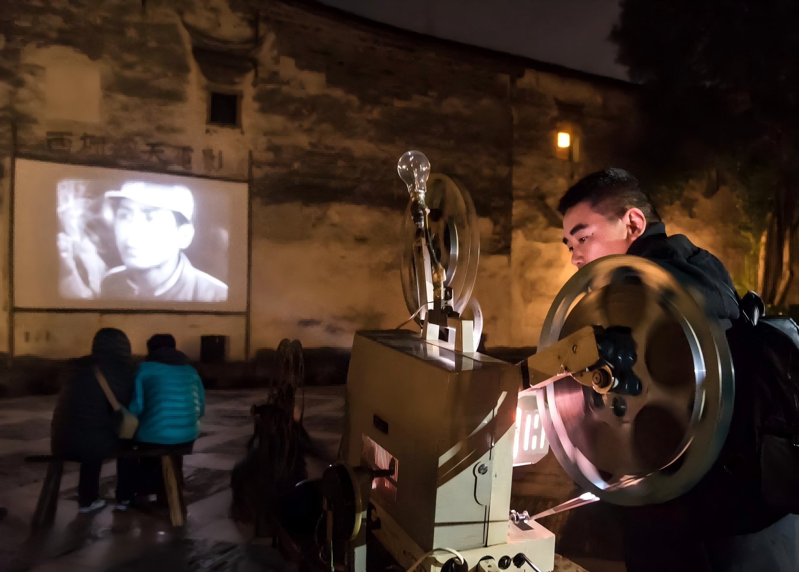 圖說一：一台舊式的電影放映機正不停的轉動，斑駁的白牆上《董存瑞》正在繼續着他的不朽壯舉.jpg